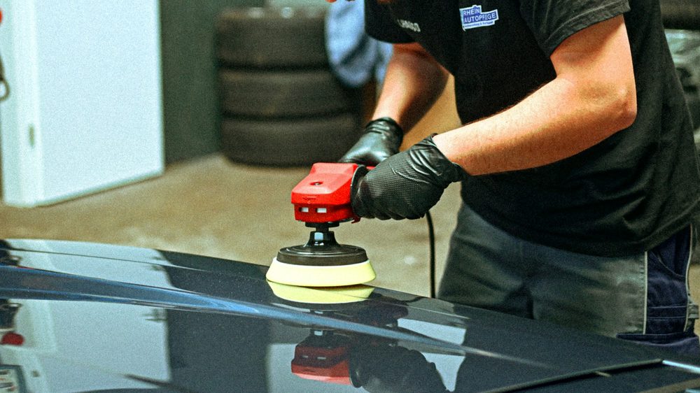 A machine polisher cutting swirl marks out of a dark panel