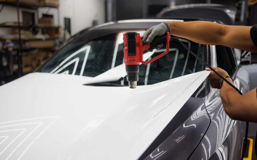 A fitter heat-setting white film down over a bonnet in the bay